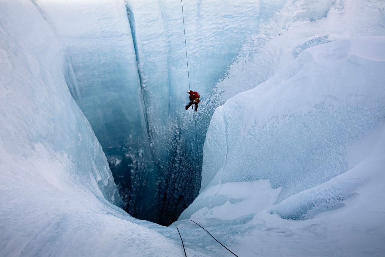 INTO-THE-ICE_Alun-Hubbard-descending-into-the-Moulin-hole_credit-Lars-H.-Ostenfeld-